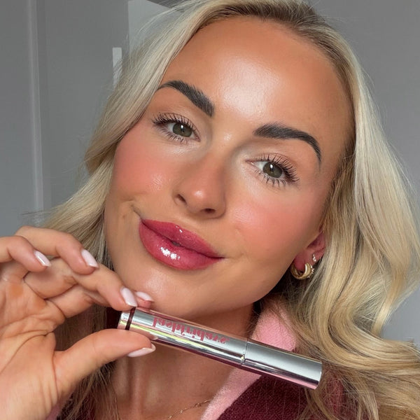 Model wearing Lash Fridays peel-off lip stain, holding the tube